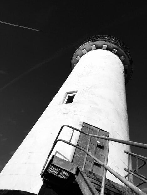 A detailed close-up of the Cape Hatteras Lighthouse, showcasing its black and white spiral stripes and the intricate brickwork of the structure.