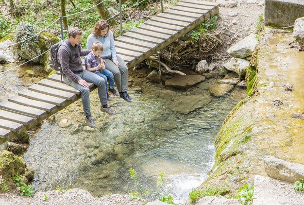 A group of hikers carefully navigating a rocky riverbed near a waterfall, demonstrating the importance of caution and proper footwear in such environments.