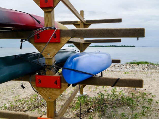 A close-up of various kayaking essentials, including a paddle, PFD (personal flotation device), dry bag, and waterproof map case, neatly arranged on a wooden dock.