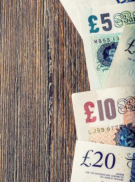 A close-up shot of various currency bills (USD, EUR, GBP) scattered on a table, partially covered by a travel insurance policy document, with a pair of eyeglasses resting on top; the image conveys a sense of careful financial planning for travel.