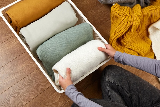 A person using packing cubes to compress and organize clothes in a suitcase, demonstrating the space-saving benefits of the cubes. The focus is on the hands carefully folding garments and placing them into a cube.