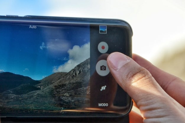 A close-up shot of a smartphone displaying its camera settings interface. Various options like ISO, white balance, and focus adjustments are visible on the screen. The hand of the user is slightly blurred, indicating a dynamic adjustment.