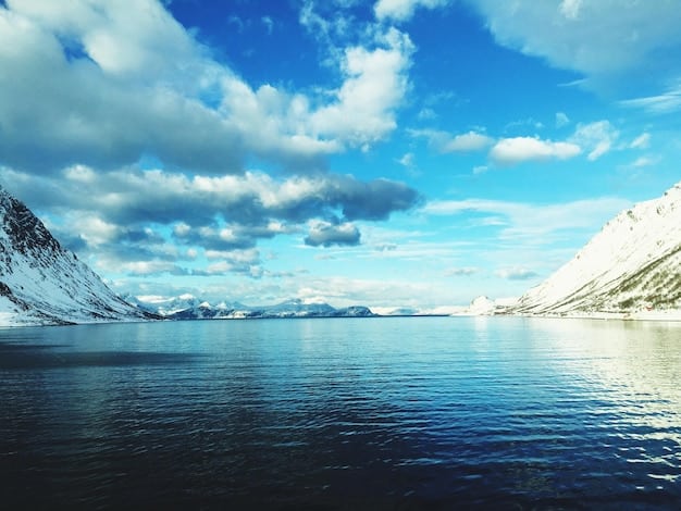 A vibrant, clear blue glacial lake with snow-capped mountains in the background, reflecting the sky. There's a small boat gently gliding across the water, and lush green forests line the shores, capturing the serene beauty of the Pacific Northwest.
