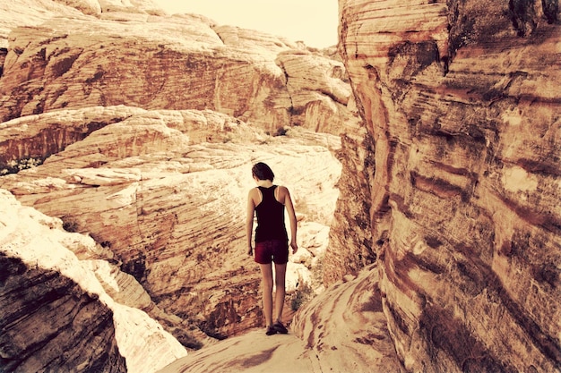 A lone hiker standing in awe before ancient petroglyphs carved into a red rock cliff at a quiet national monument, illustrating discovery and respect for history.